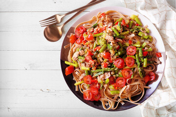 Pasta with tuna and fresh tomatoes and asparagus. Overhead view table scene on a white wood...