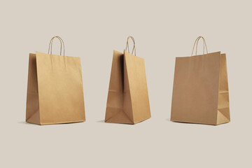 three brown paper shopping bags isolated on beige background, eco-friendly packaging, shopping, delivery concept