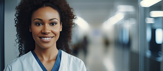 Smiling biracial female healthcare worker in hospital corridor open area for copy medical services