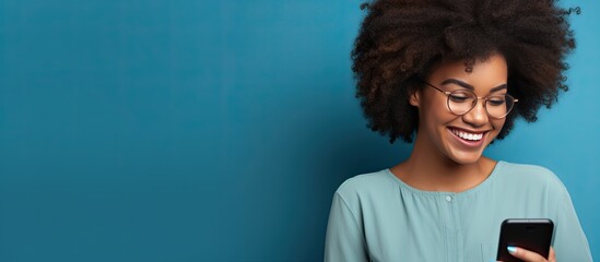 Happy dark skinned Afro American woman poses against blue background pointing to empty space for advertising