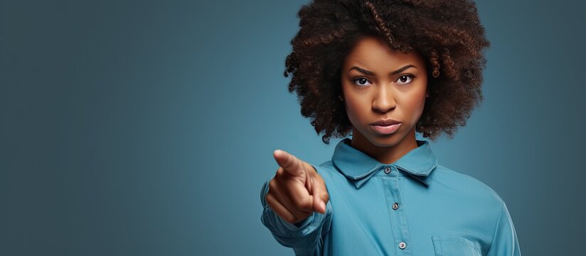 A calm African American woman in casual attire pointing to an advertisement with a serious expression