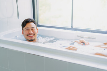 Funny asian man play and pose in a bathtub in the bathroom.