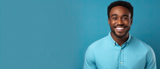 Smiling black man in blue shirt against blue background looking at camera