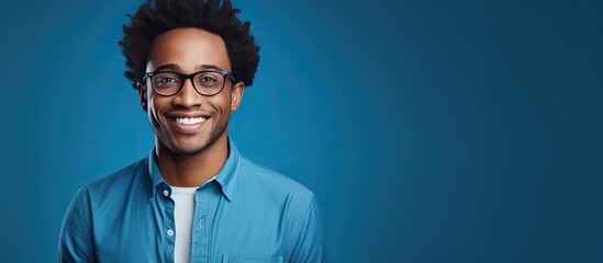 Portrait of a smiling African American man wearing glasses posed against a blue background