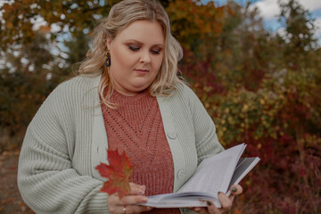 Beautiful plus size model walking in the fall park against yellow leaves/ Woman wearing warm...