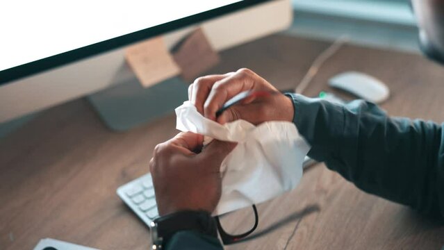 Night, tissue and a businessman cleaning glasses for vision, computer or reading support. Dark, desk and a corporate Asian employee wiping eyewear for clear lens on a pc in an office during overtime