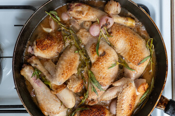 Chicken with sherry vinegar and tarragon sauce in a pan on gas cooker. Top view. Close-up.
