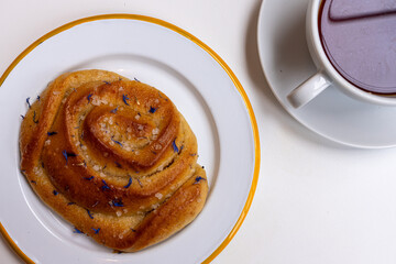 Delicious sweet golden lemon pastry with bergamot petals, served on a plate. Tea and bun refreshment. Coffee break concept. Top view, close-up.