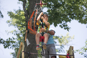 School boy preparing for zipline adventure.  Summer fun with climbing in mountains. Enjoying  time in climbing adventure park on warm and sunny summer day. Summer activities for young kids.