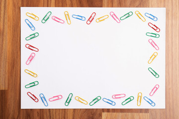 Top view of blank paper with paperclip frame in wooden background