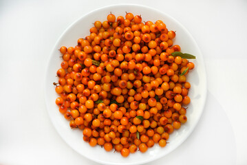Orange sea buckthorn berries on a white plate. Hippophae.