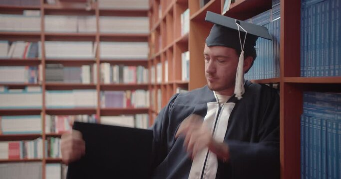 Student showing that the diploma is achievable after graduating from university, proudly holding his diploma in the library