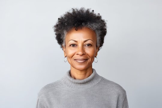 Studio Portrait Of Stylish Middle Age Smiling 50 - 55 Year Old Woman Posing On Grey Background