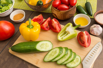 Different vegetables for cooking salad on cutting board with knife on table on kitchen. Healthy vegetarian vegan diet food