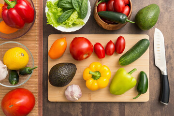 Different vegetables for cooking salad on cutting board with knife on table on kitchen. Healthy vegetarian vegan diet food