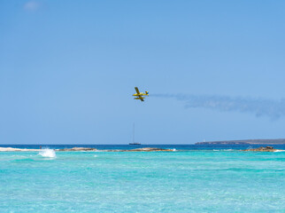 An aircraft releasing water while flying over the blue sea of Formentera