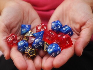 Hands of a person holding a lot of RPG DND dice on a white background 