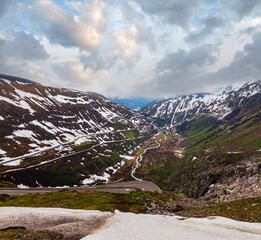 Fototapeta na wymiar Spring cloudy overcast mountain landscape with serpentine road on Furka Pass, Switzerland.