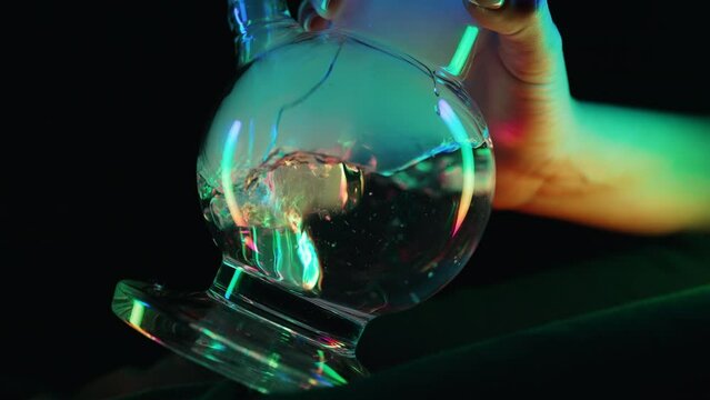 Macro smoking marijuana with glass water bong in neon light at home. Cannabis.