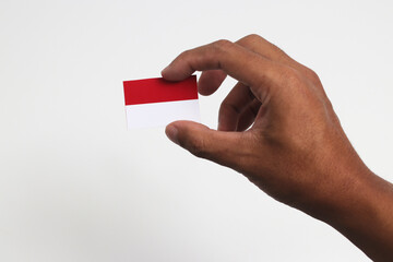 Hand holding Indonesia flag with empty copy space isolated on white background