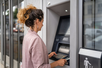 woman using credit card and withdrawing cash at the ATM