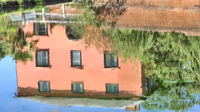 House and humpback bridge reflected in duck pond with passing van in Finchingfield, Essex, UK.