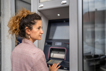 Fototapeta na wymiar woman using credit card and withdrawing cash at the ATM