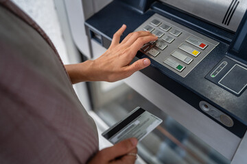 hands of woman using credit card and withdrawing cash at the ATM