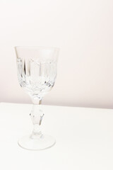 Vintage crystal glass in front of beige background. Place for text.