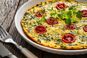 Omelette  - scrambled eggs with oregano, thyme, spinach and cherry tomatoes on wooden table
