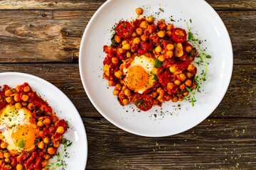 Shakshuka - fried eggs with vegetables on wooden table