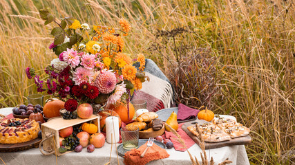 Autumn bouquet of beautiful flowers and berries in a pumpkin on wooden table in the garden. Concept of autumn festive decoration for Thanksgiving day.