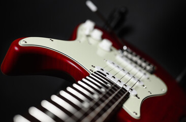 Fototapeta na wymiar Close-up of a red electric guitar on a black background. Selective narrow focus on pickup.
