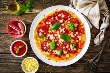 Upside down pizza with salami, mozzarella cheese and tomato sauce on wooden table