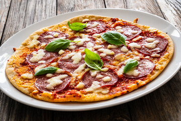 Upside down pizza with salami, mozzarella cheese and tomato sauce on wooden table
