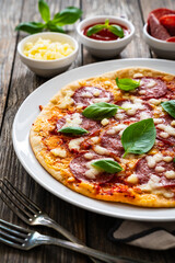 Upside down pizza with salami, mozzarella cheese and tomato sauce on wooden table