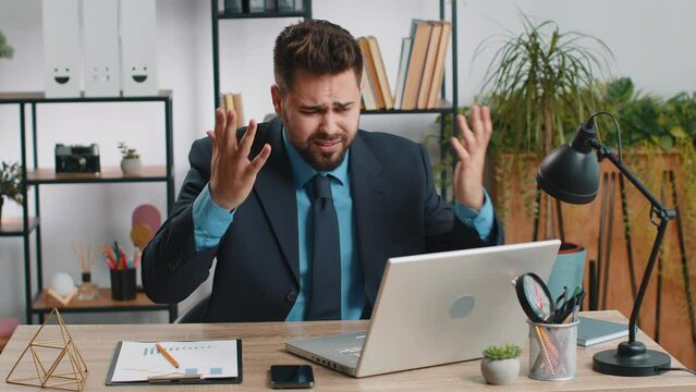 Irritated tired Caucasian business man while working on laptop, unexpected online website problem, computer virus data loss by hacking. Freelancer feeling mad about broken notebook at office workplace