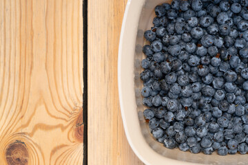 blueberries in a bowl stand on a wooden table top view
