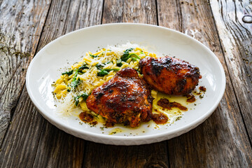 Greek style roasted chicken thighs with kritharaki rice and spinach on wooden table
