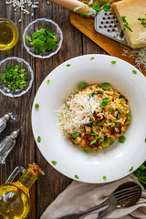 Risotto with sun dried tomatoes and Parmigiano Regiano  on wooden table
