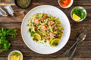 Tagliatelle with salmon and dill on wooden table
