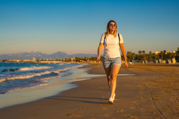 Fototapeta na wymiar Beautiful woman walking on sunny beach - Costa Dorada Spain 