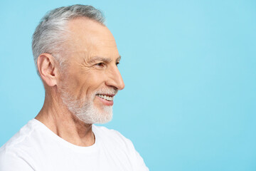 Elderly gray haired man wearing white t shirt isolated on blue background, copy space, face profile