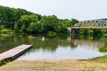 A man and woman heading out on the Allegheny River from the Tidioute Boat Ramp on kayaks in Tidioute, Pennsylvania, USA on a sunny summer day