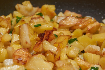 Fried potatoes with green onions and spices. Close-up.