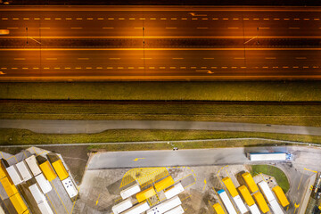 View from a height in the evening of a large parking lot with trucks and trailers by the road