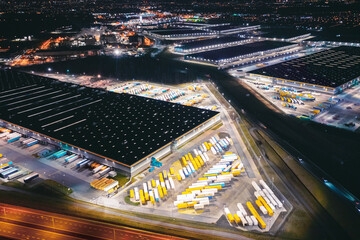 Many warehouses in an industrial area, aerial view of brightly lit logistics warehouses at night, trading business