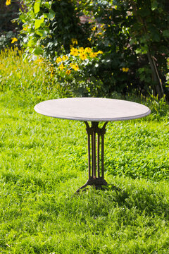 Empty circular marble table located on a very striking green grass