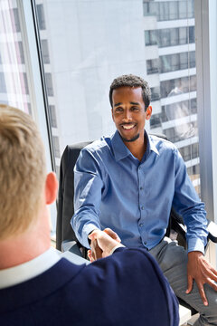 Diverse happy business men handshaking at meeting. Male manager shaking hand of corporate client or investor making partnership contract with investor at professional work meeting in office. Vertical