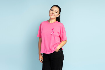 Portrait of  smiling asian woman wearing  t shirts with breast cancer pink ribbon isolated on blue...